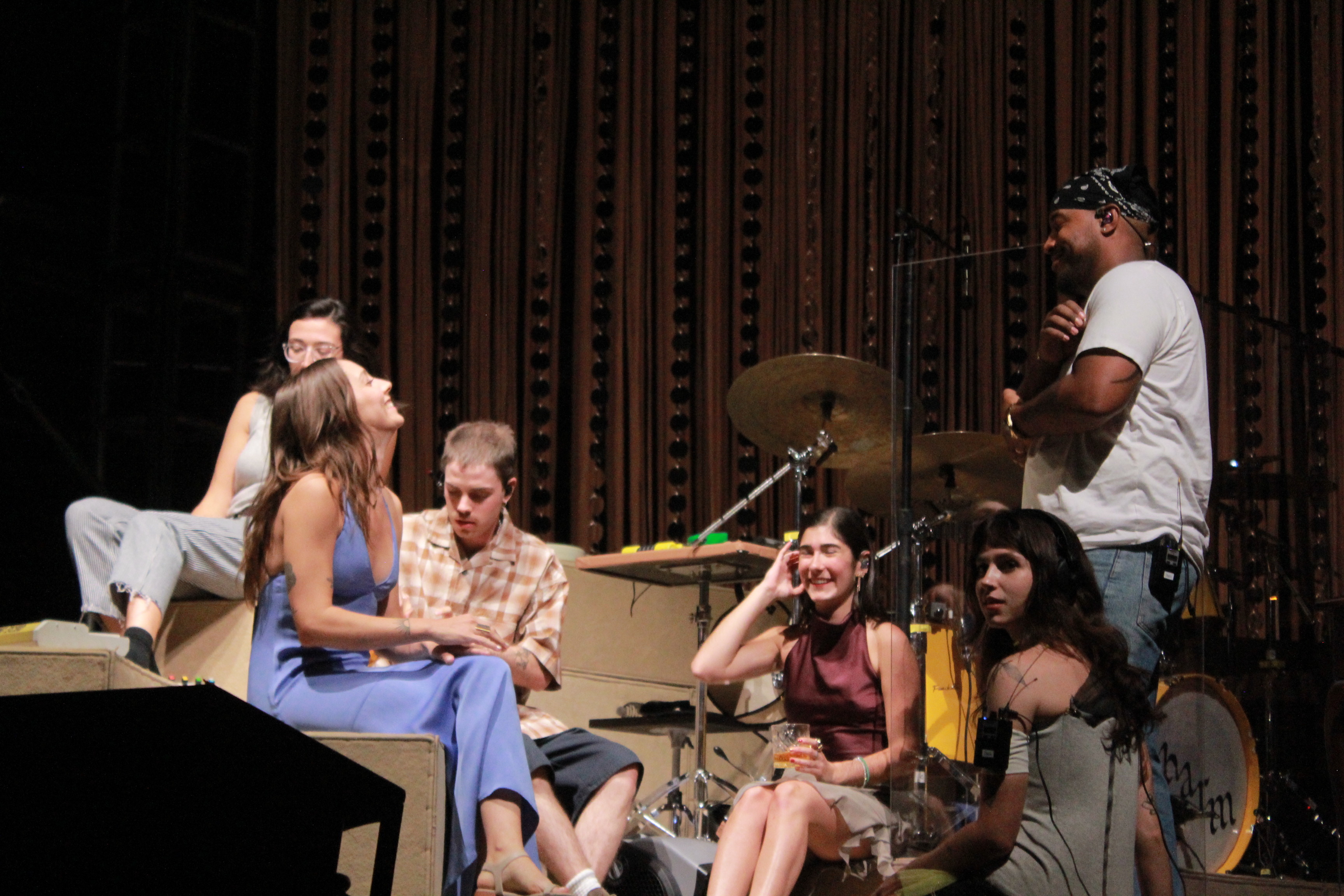 Clairo chatting and sitting on stage with her band